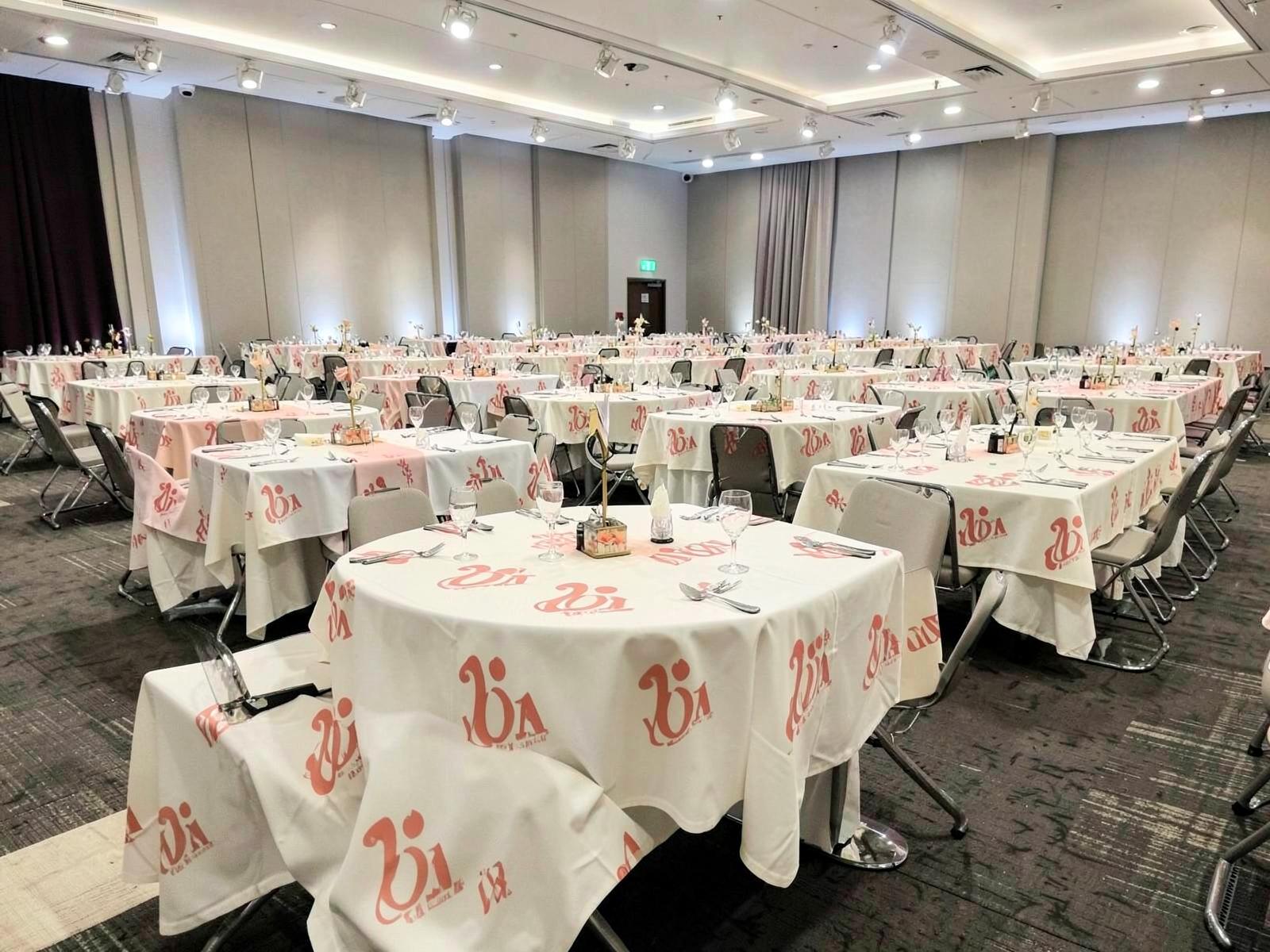 Rows of matching branded custom table cloths on multiple tables at an event hall