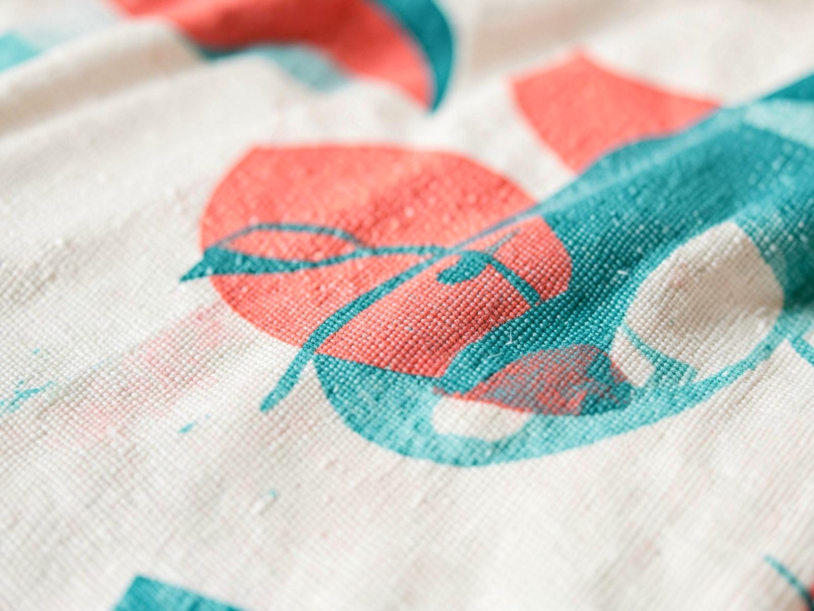 Macro close-up of dye-sublimation printed coral and teal artwork on cream table cloth fabric
