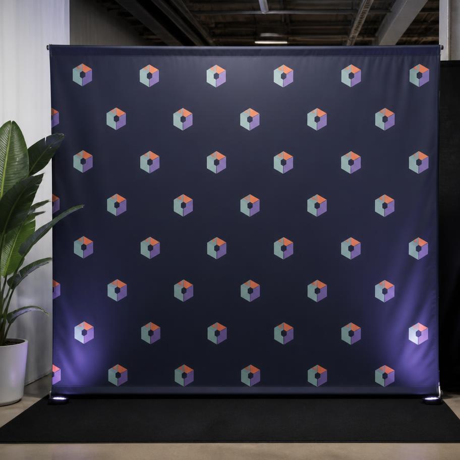Branded step-and-repeat fabric tapestry backdrop behind a trade-show photo area