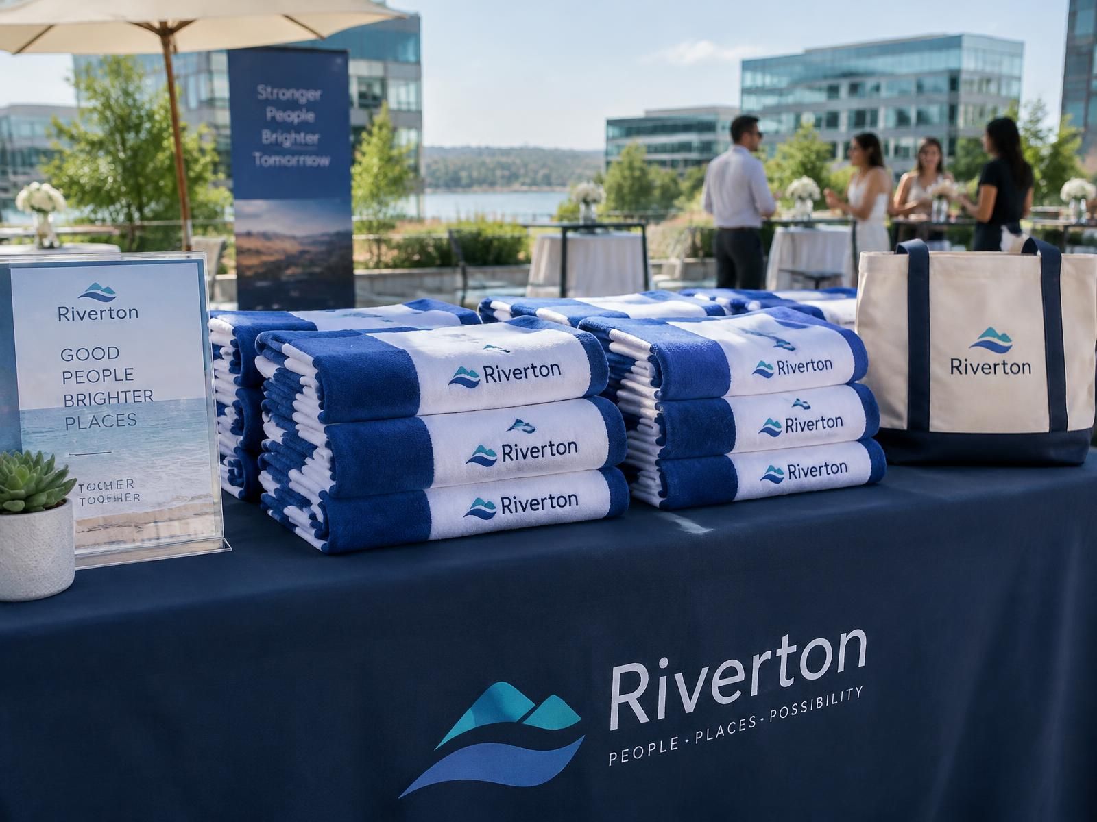 Folded branded beach towels with a company logo displayed on a giveaway table