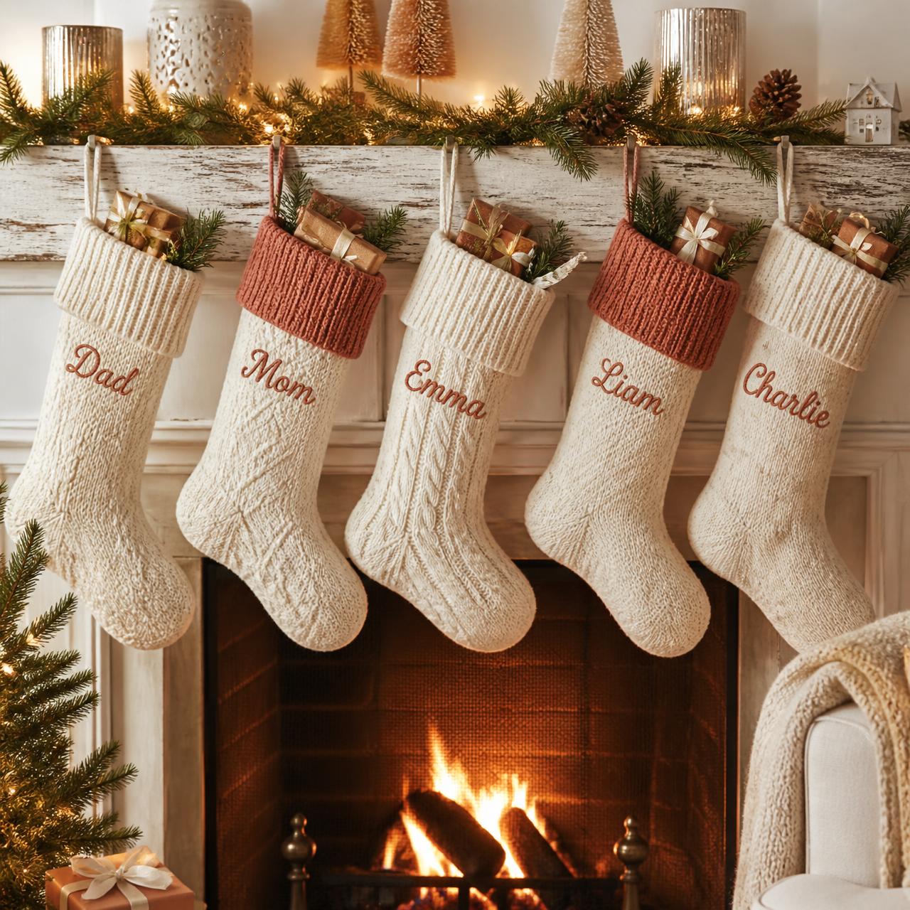 Row of personalized cable-knit Christmas stockings with embroidered family names hanging on a rustic mantel