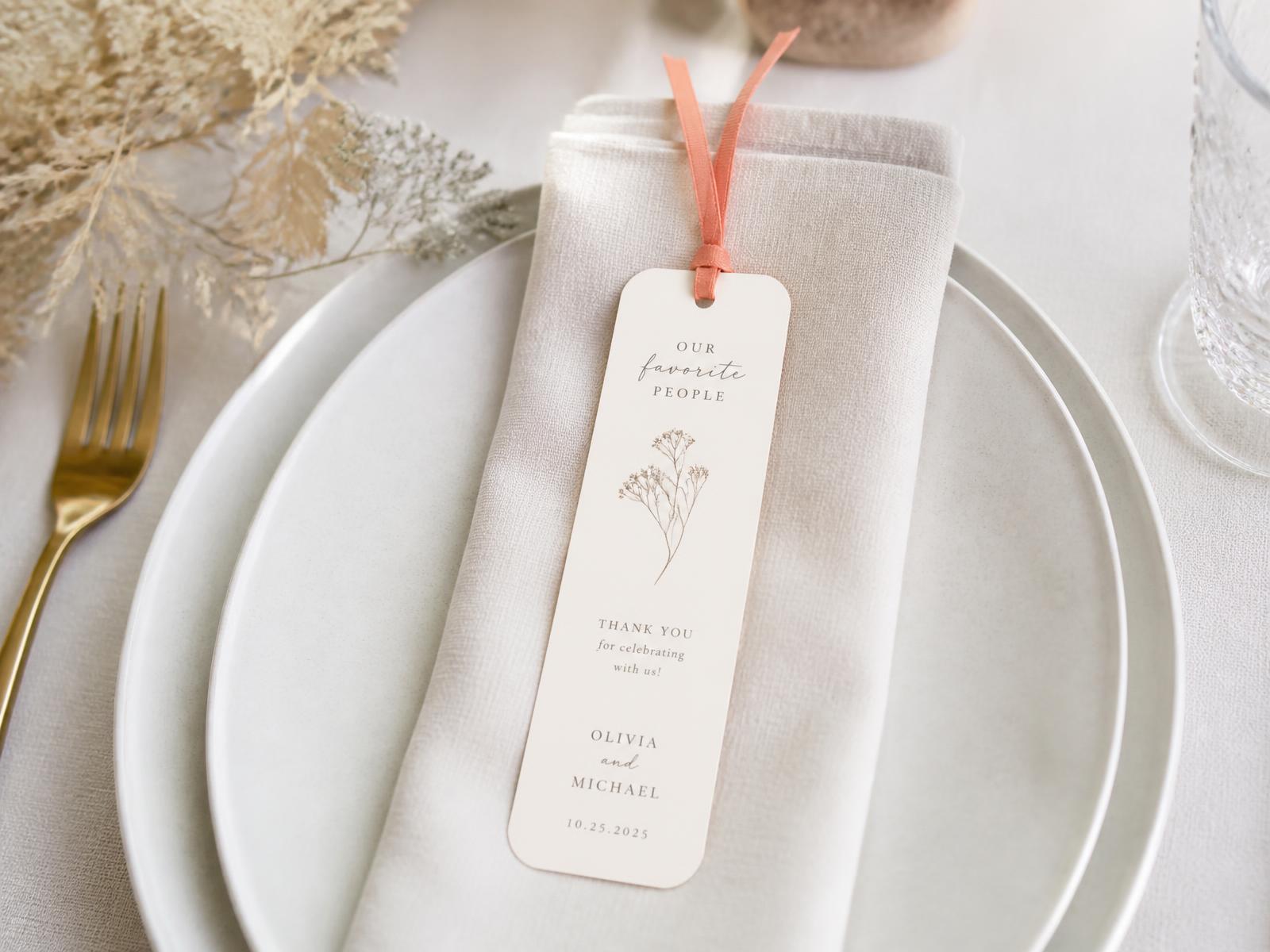 Rounded-corner custom bookmarks with ribbons arranged as wedding favors on a table setting