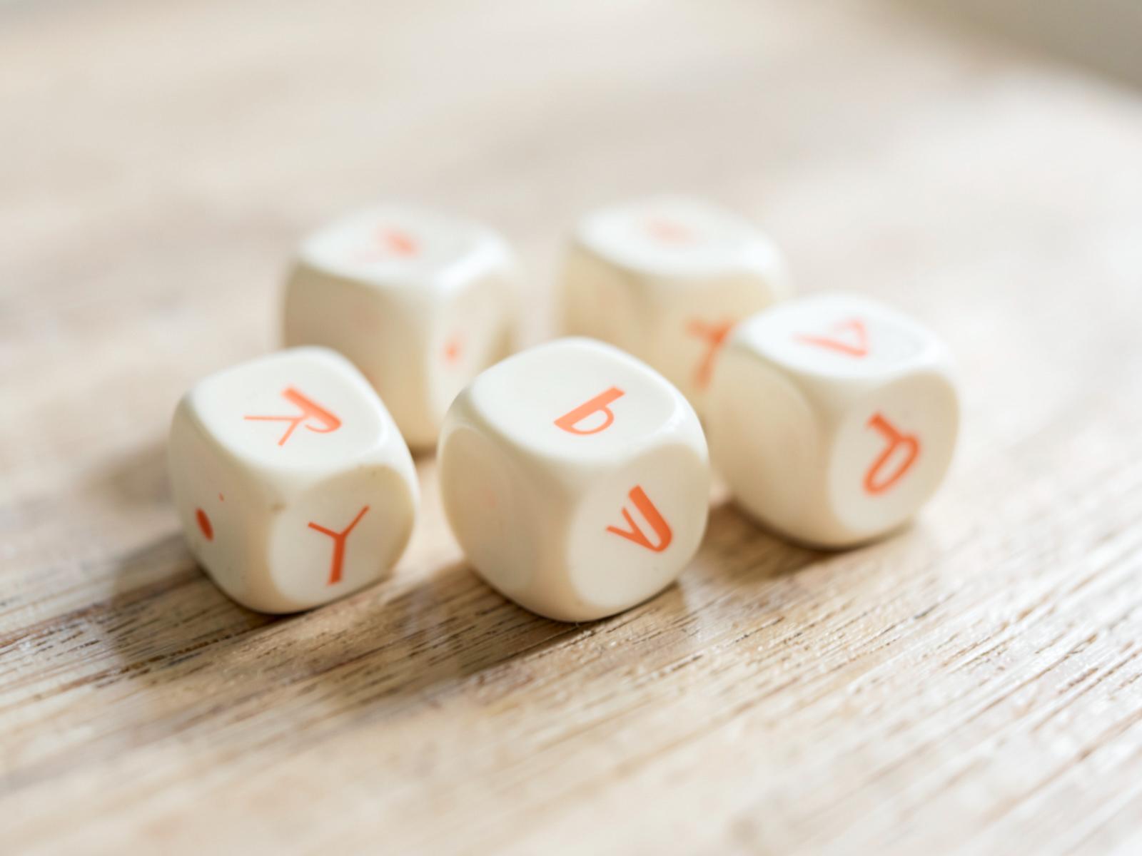 Cream custom six-sided dice printed with a coral logo beside a translucent polyhedral dice set on a table